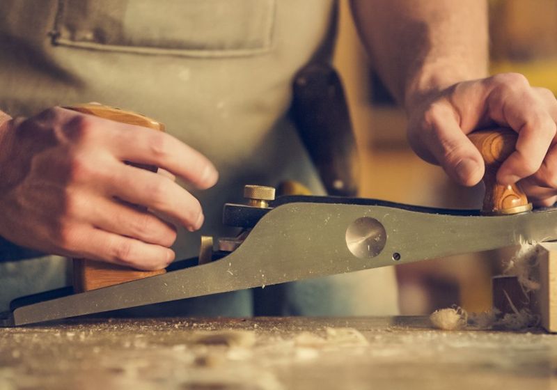 Carpenter hand-planing a piece of timber